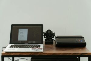 A creative home office setup featuring a laptop, printer, and artistic design work.