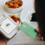 A person holding a credit card next to a bowl of food